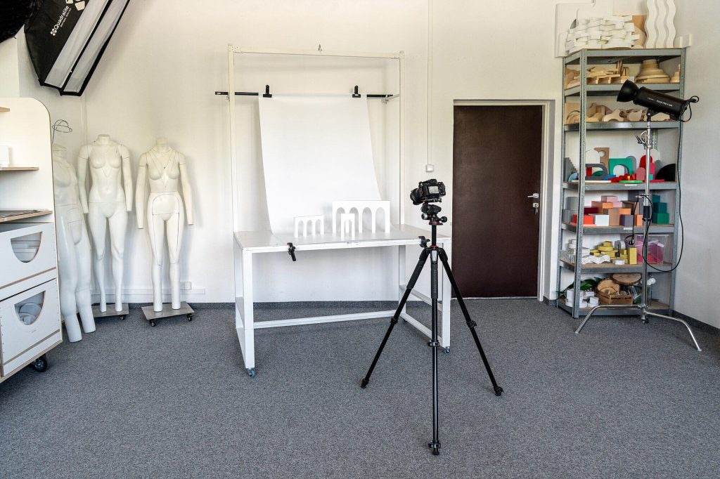Stół do zdjęć produktowych z białym tłem, aparat na statywie i lampa studyjna — Studio CYNAMON Warszawa
